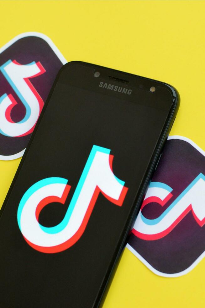 Tiktok logo on samsung smartphone screen on yellow background. TikTok is a popular video-sharing social networking service owned by ByteDance photo