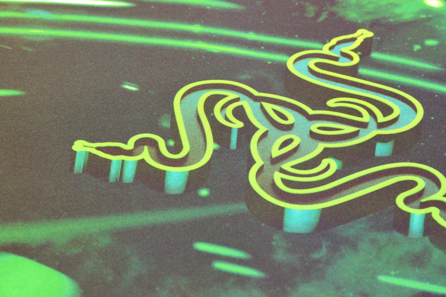 Razer Goliathus Speed Gaming green mouse pad with logo of three snakes tribal on dark background photo
