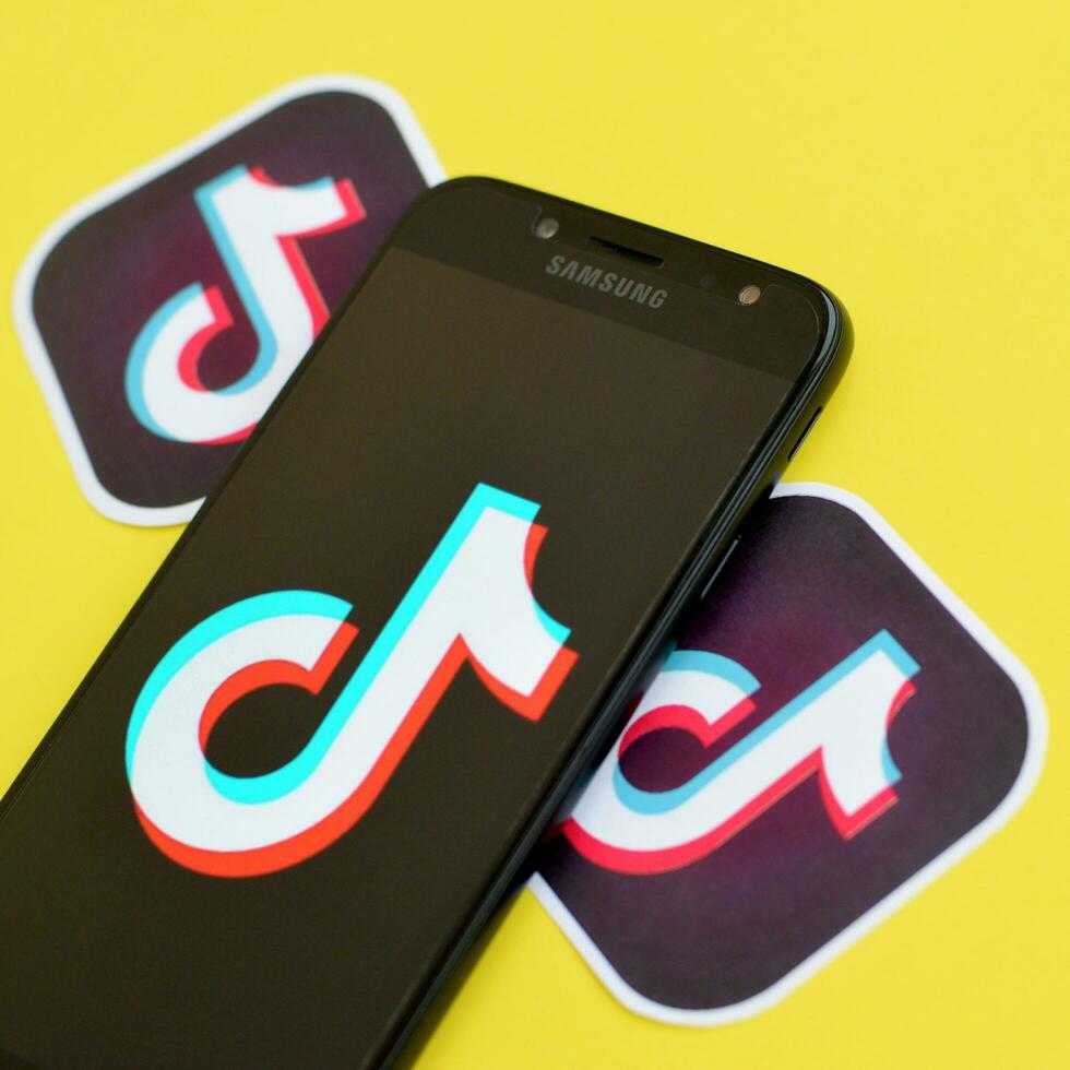 Tiktok logo on samsung smartphone screen on yellow background. TikTok is a popular video-sharing social networking service owned by ByteDance photo