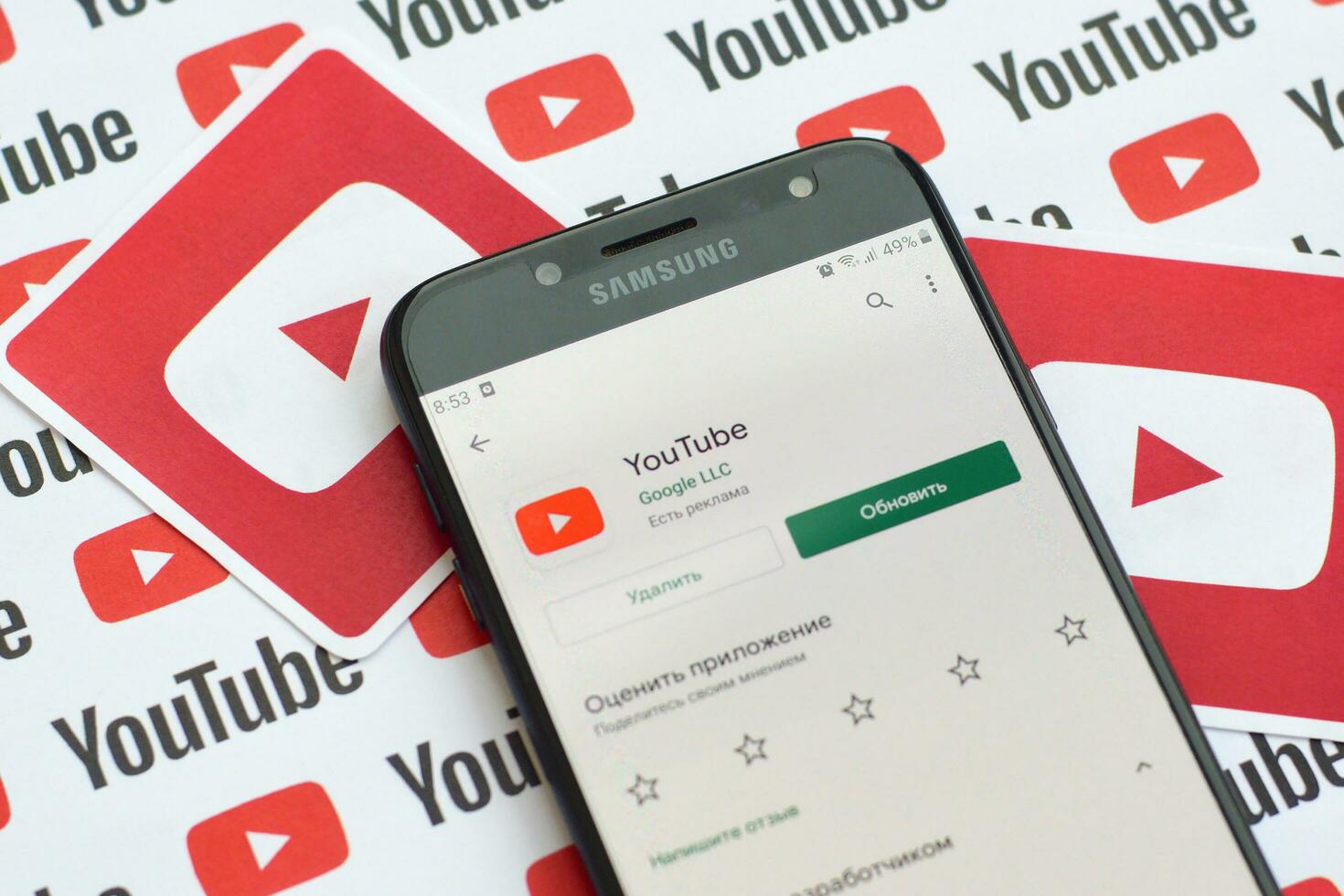 Youtube app on samsung smartphone screen on paper banner with small youtube logos and inscriptions. YouTube is Google subsidiary and American most popular video-sharing platform photo