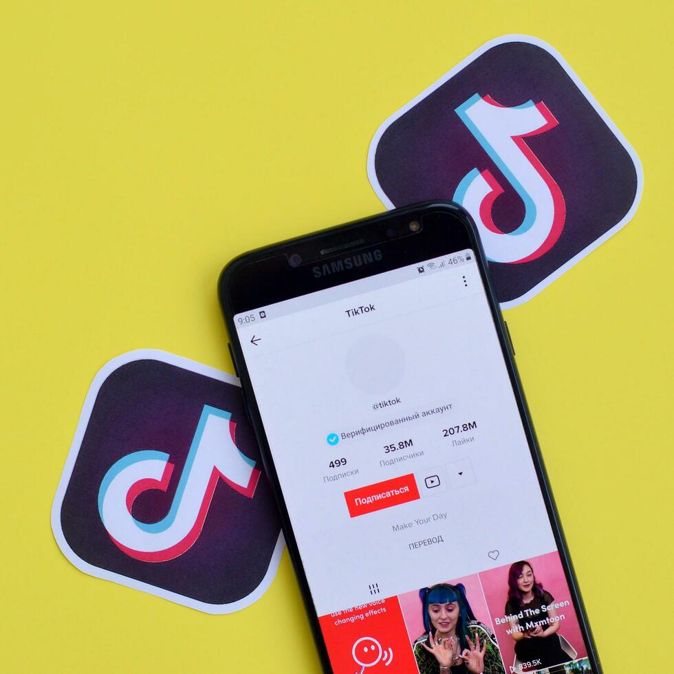 Tiktok application on samsung smartphone screen on yellow background. TikTok is a popular video-sharing social networking service owned by ByteDance photo