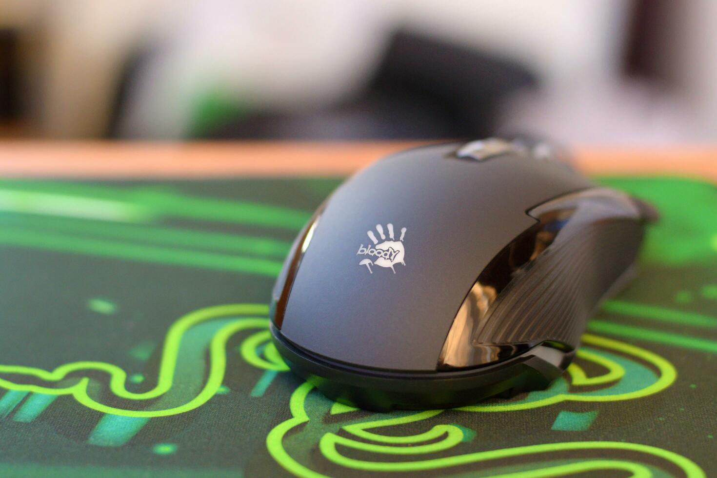 P93 Bloody cybersport gaming mouse by A4Tech lies on Razer Goliathus mouse pad. Professional cybersport supply photo