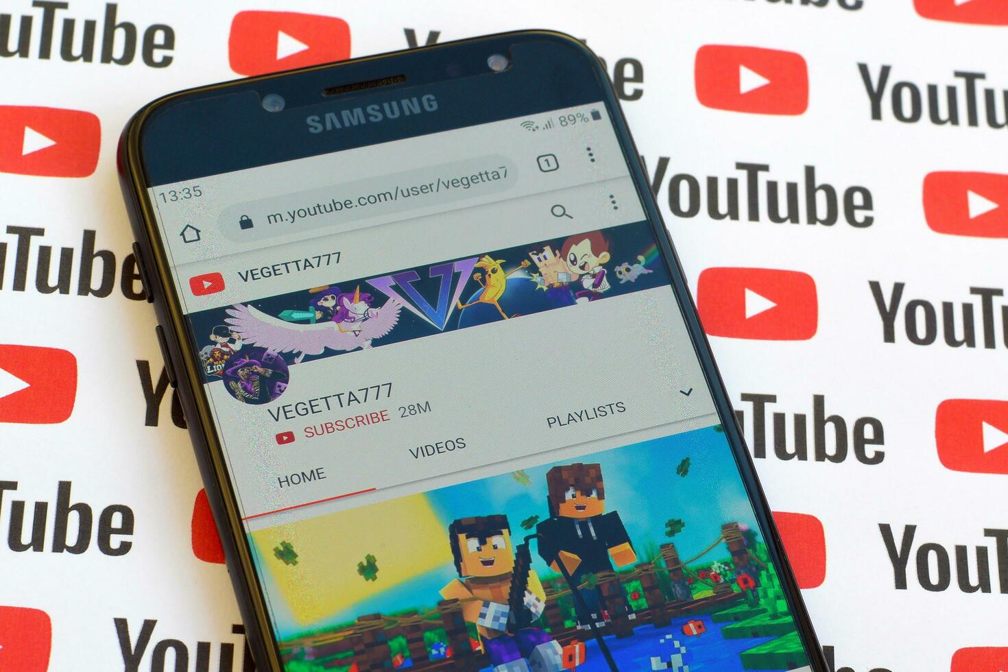 Vegetta777 official youtube channel on smartphone screen on paper youtube background. photo