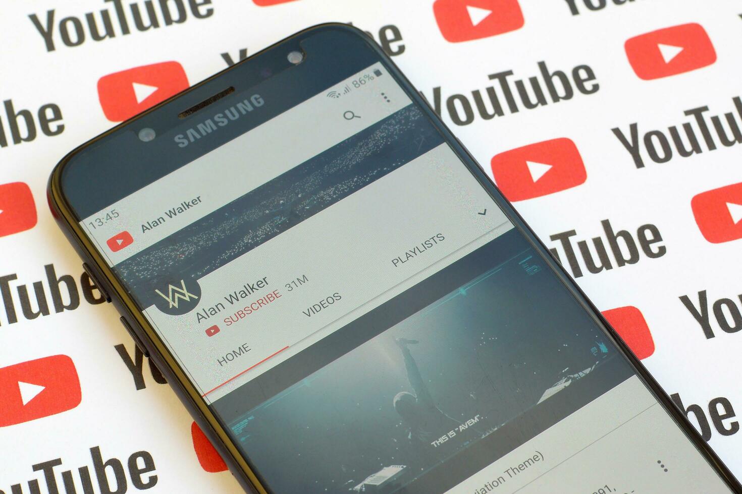 Alan Walker official youtube channel on smartphone screen on paper youtube background. photo