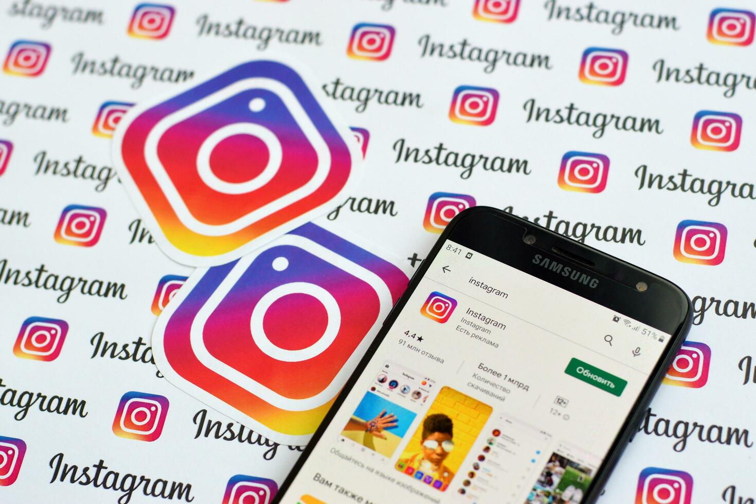 Instagram app on samsung smartphone screen on banner with small instagram logos. Instagram is American photo and video-sharing social networking service by Facebook inc
