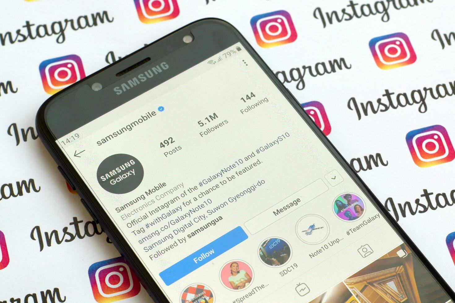 Samsung mobile official instagram account on smartphone screen on paper instagram banner. photo