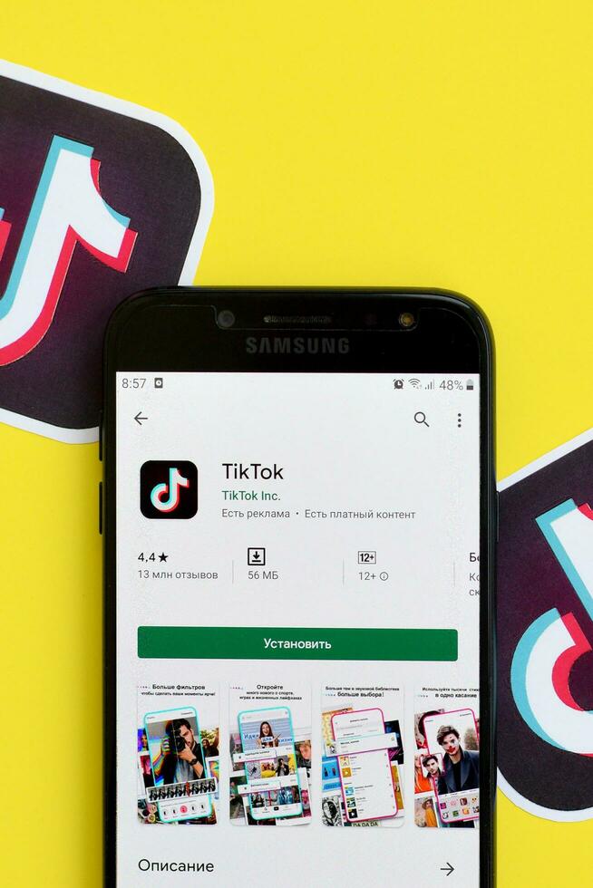 Tiktok application in playmarket on samsung smartphone screen on yellow background. TikTok is a popular video-sharing social networking service owned by ByteDance photo