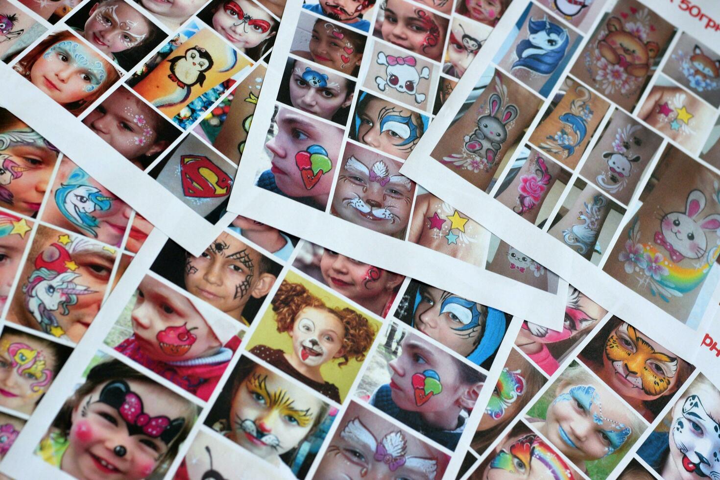 Many catalog pages with printed kids portraits with colorful face painting photo