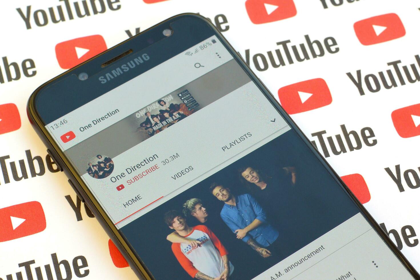 One Direction official youtube channel on smartphone screen on paper youtube background. photo
