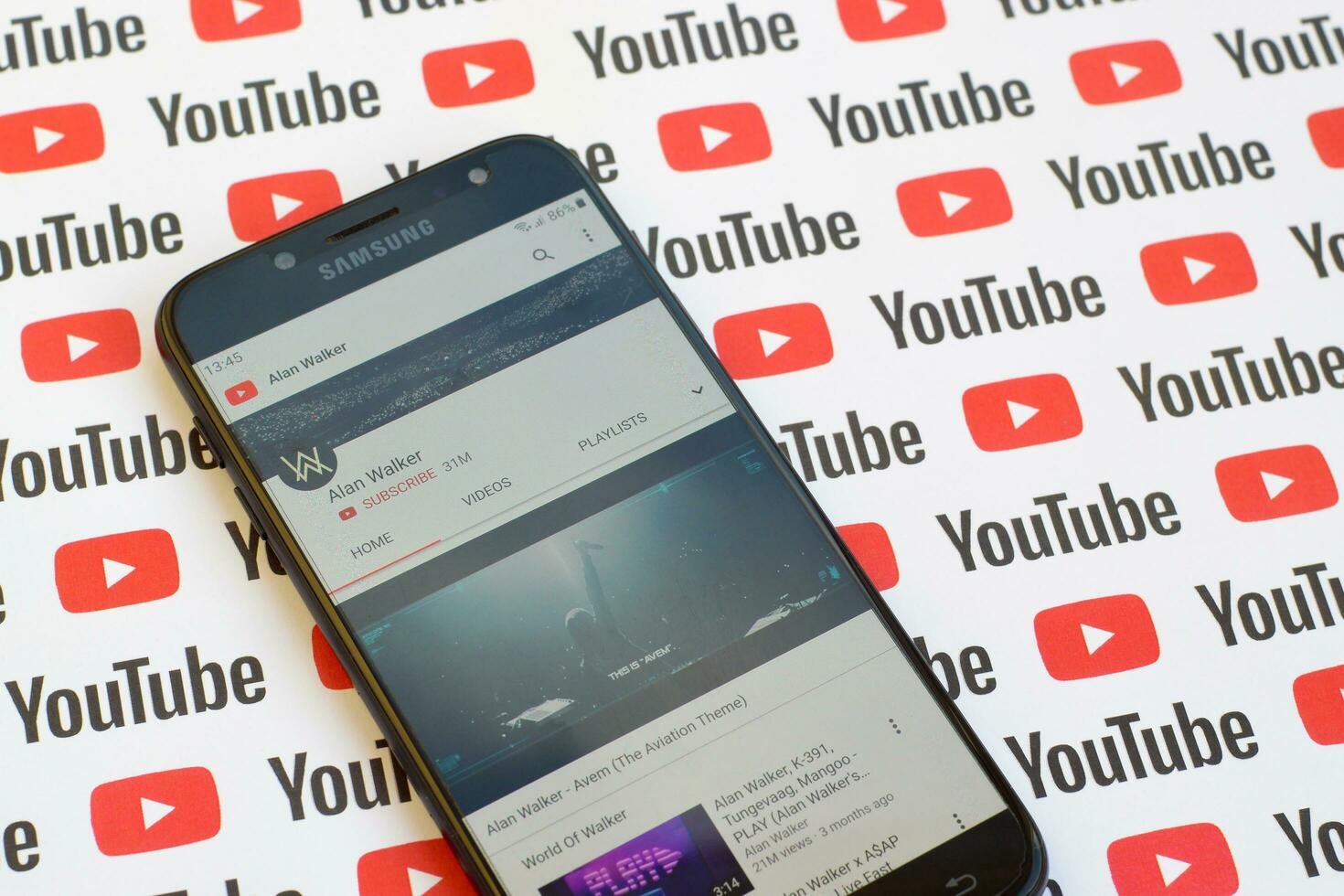 Alan Walker official youtube channel on smartphone screen on paper youtube background. photo