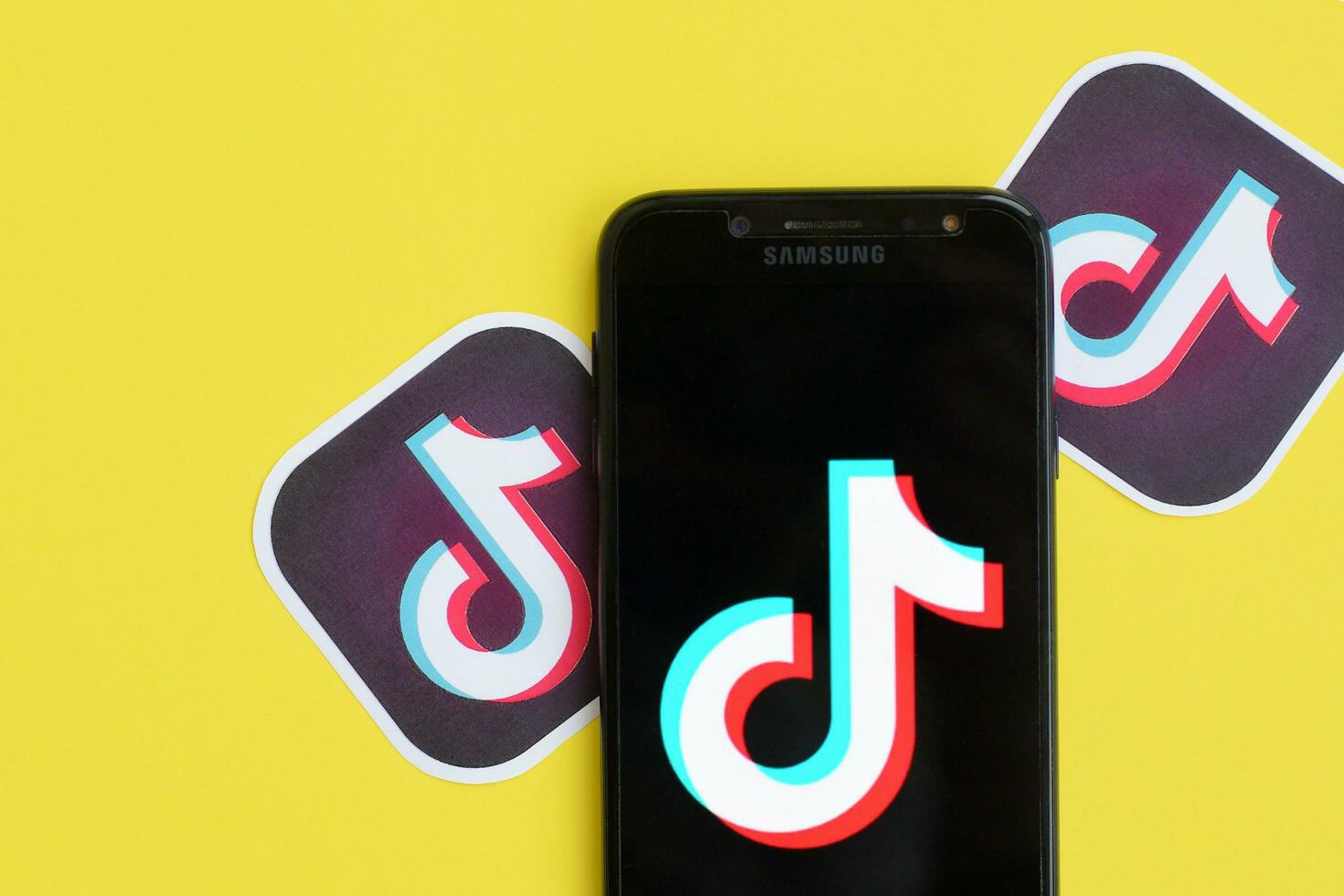 Tiktok logo on samsung smartphone screen on yellow background. TikTok is a popular video-sharing social networking service owned by ByteDance photo