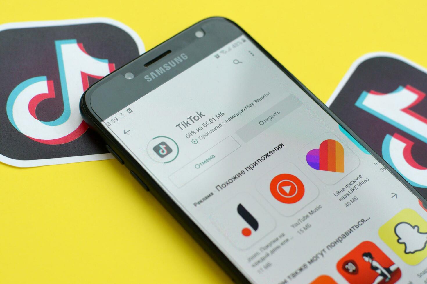 Tiktok application in playmarket on samsung smartphone screen on yellow background. TikTok is a popular video-sharing social networking service owned by ByteDance photo