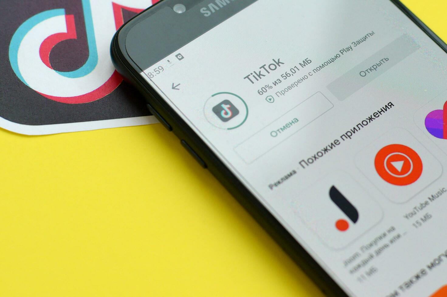 Tiktok application in playmarket on samsung smartphone screen on yellow background. TikTok is a popular video-sharing social networking service owned by ByteDance photo