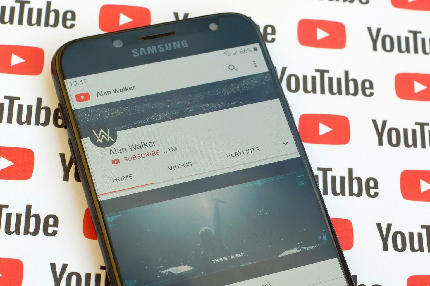 Alan Walker official youtube channel on smartphone screen on paper youtube background. photo