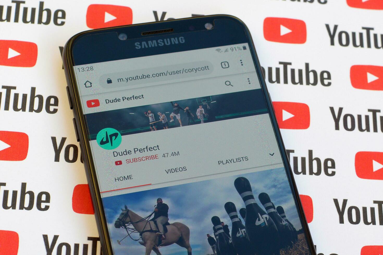Dude Perfect official youtube channel on smartphone screen on paper youtube background. photo