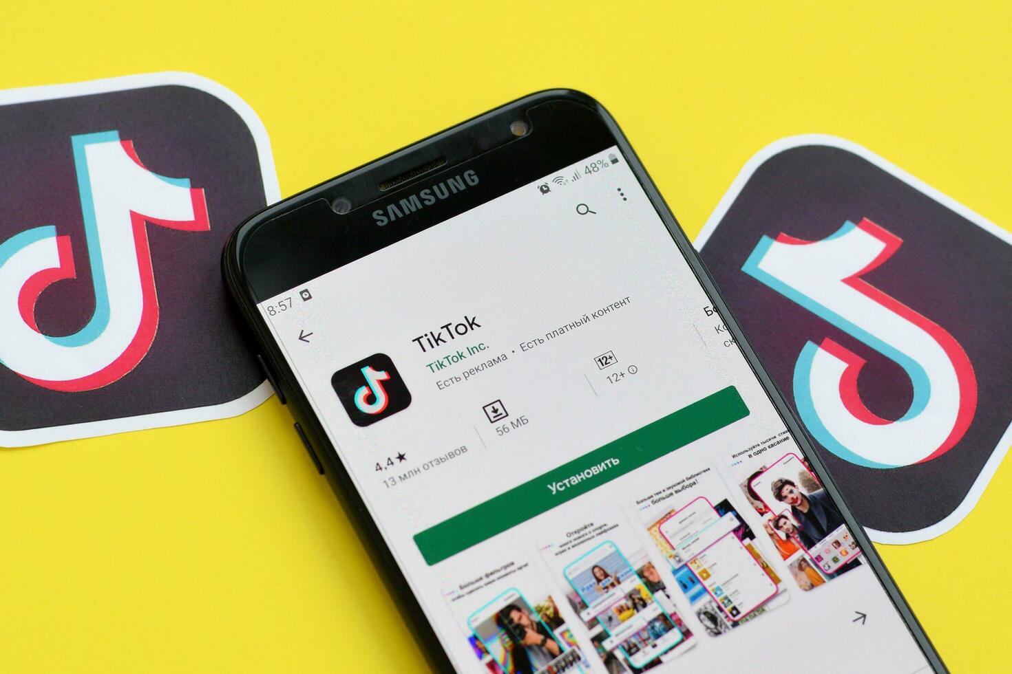 Tiktok application in playmarket on samsung smartphone screen on yellow background. TikTok is a popular video-sharing social networking service owned by ByteDance photo