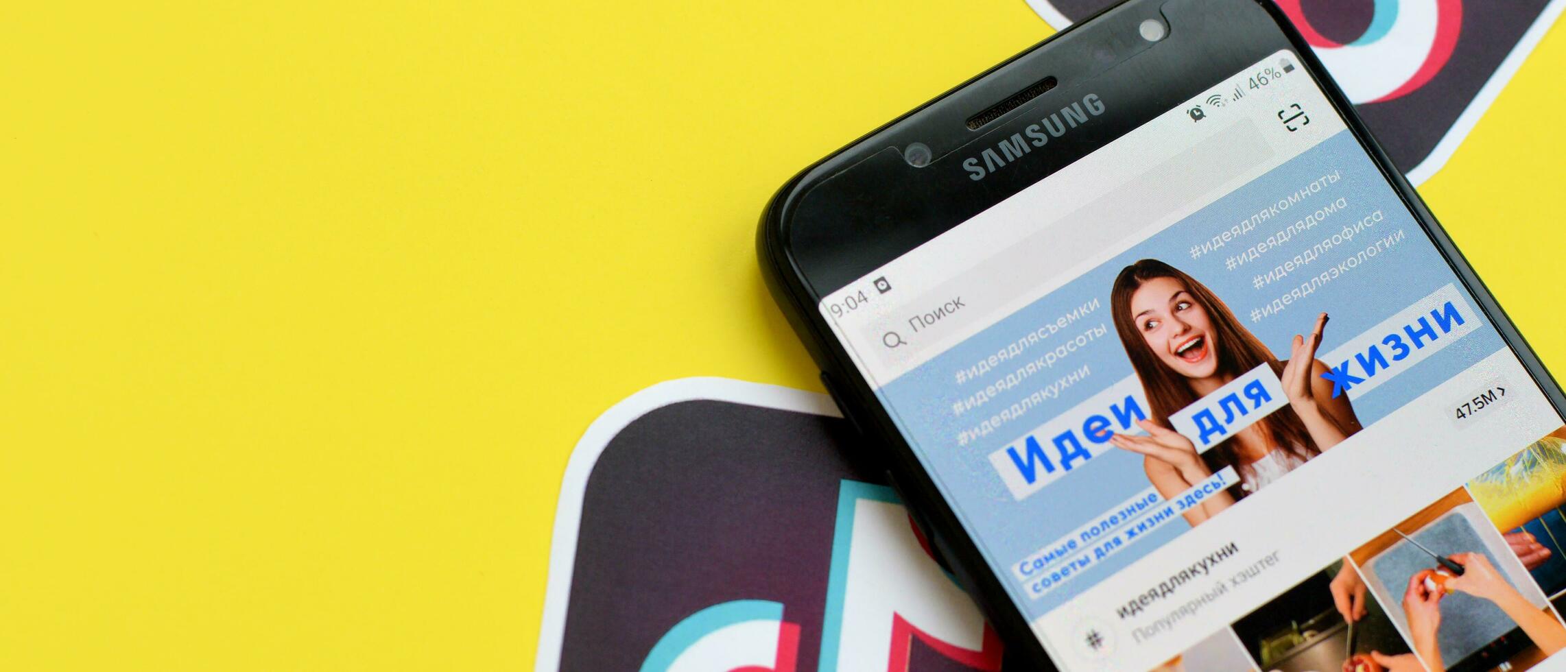 Tiktok application on samsung smartphone screen on yellow background. TikTok is a popular video-sharing social networking service owned by ByteDance photo