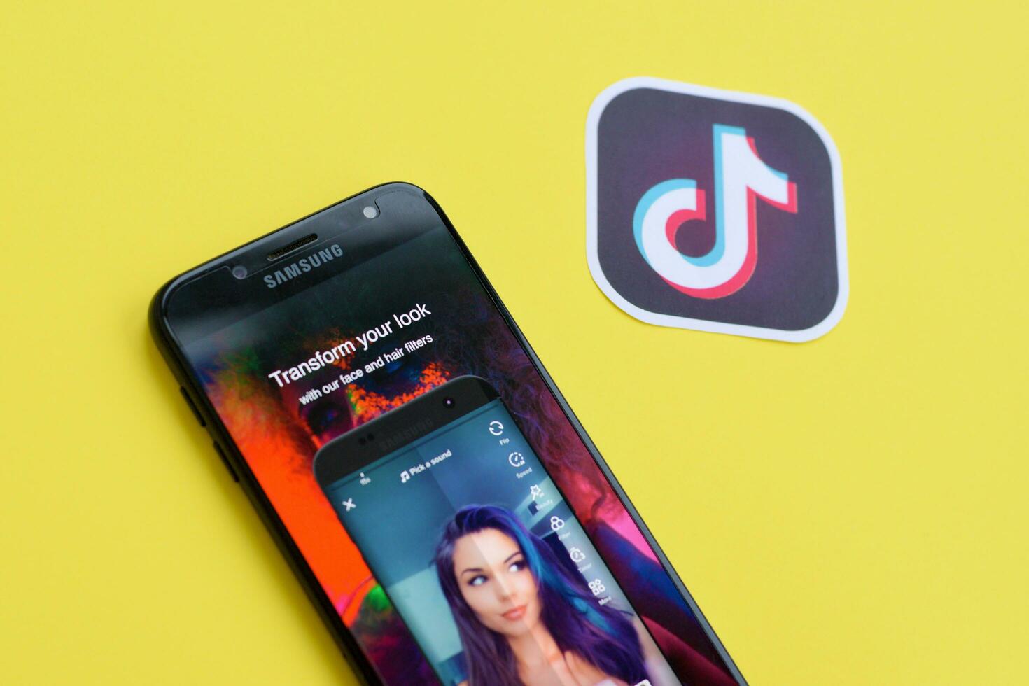 Tiktok application on samsung smartphone screen on yellow background. TikTok is a popular video-sharing social networking service owned by ByteDance photo
