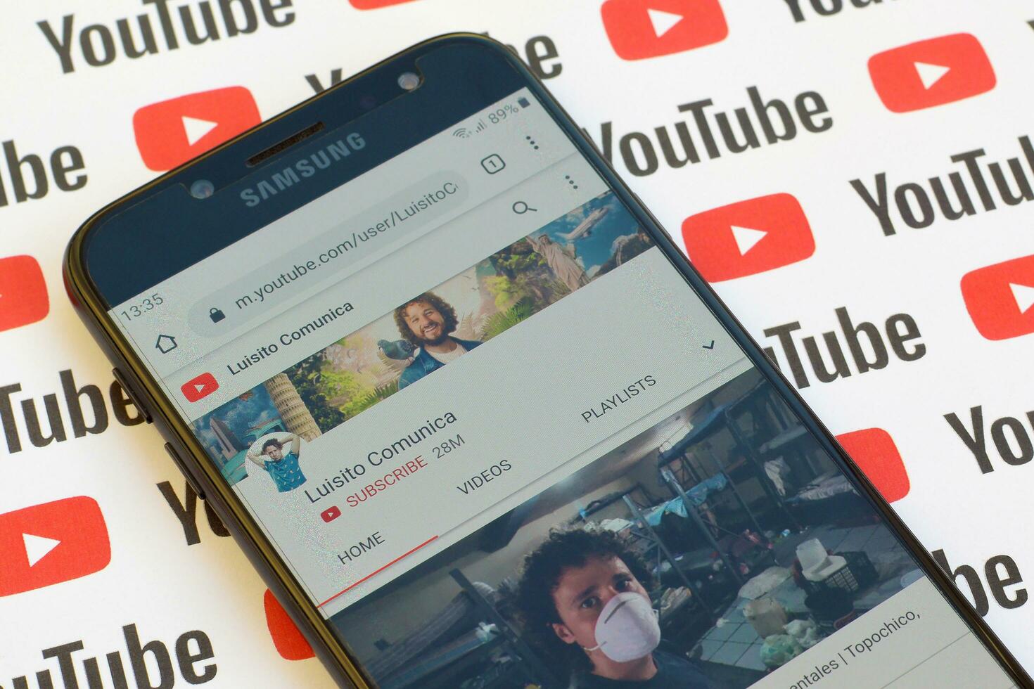 Luisito Comunica official youtube channel on smartphone screen on paper youtube background. photo