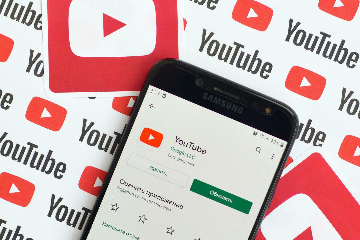 Youtube app on samsung smartphone screen on paper banner with small youtube logos and inscriptions. YouTube is Google subsidiary and American most popular video-sharing platform photo