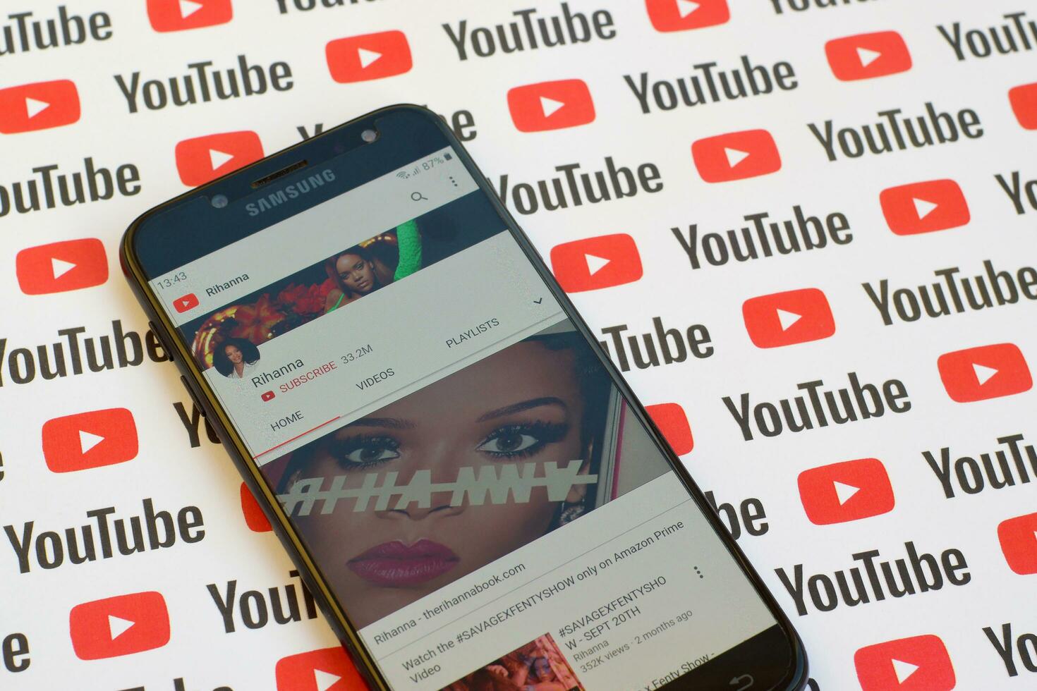 Rihanna official youtube channel on smartphone screen on paper youtube background. photo