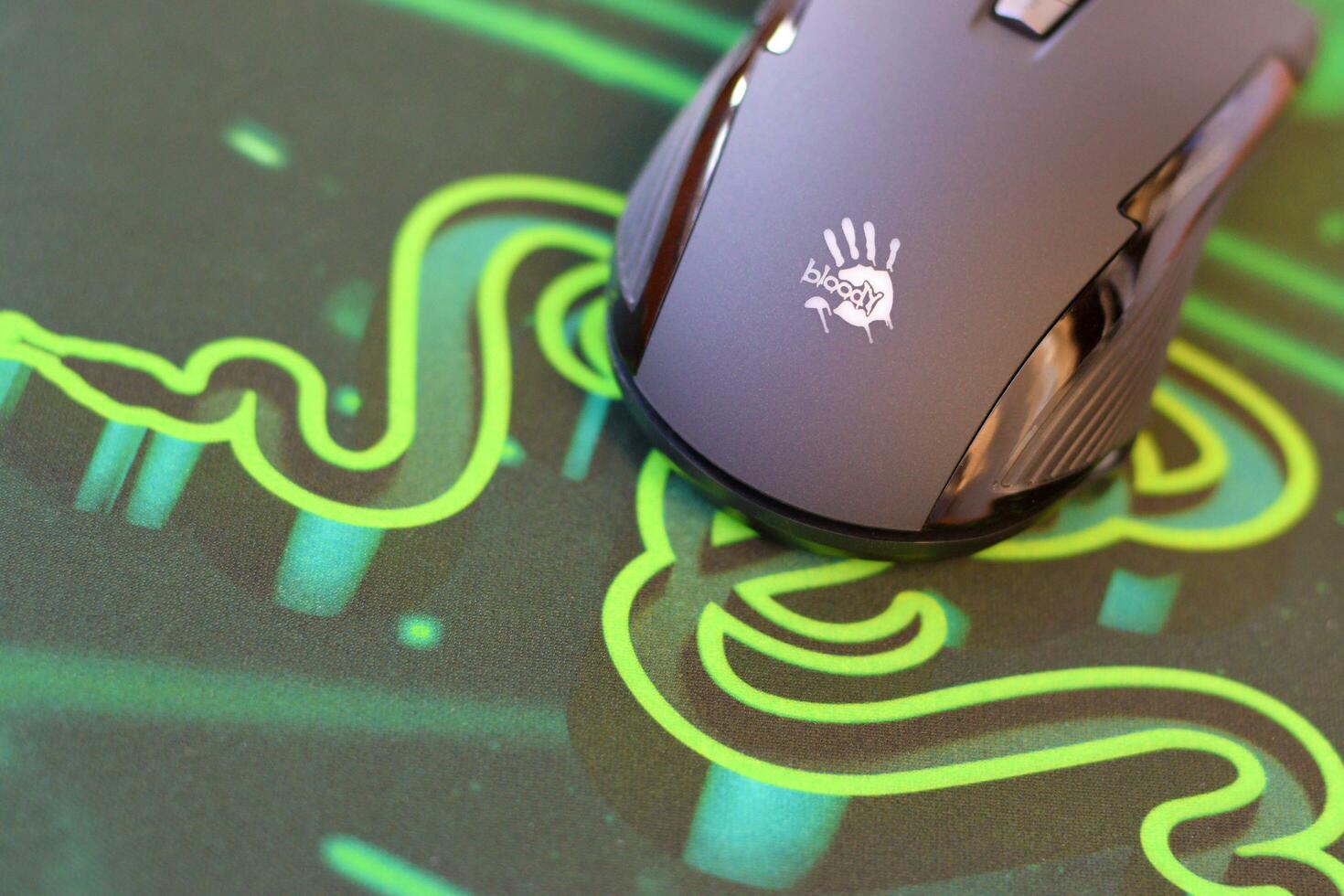 P93 Bloody cybersport gaming mouse by A4Tech lies on Razer Goliathus mouse pad. Professional cybersport supply photo