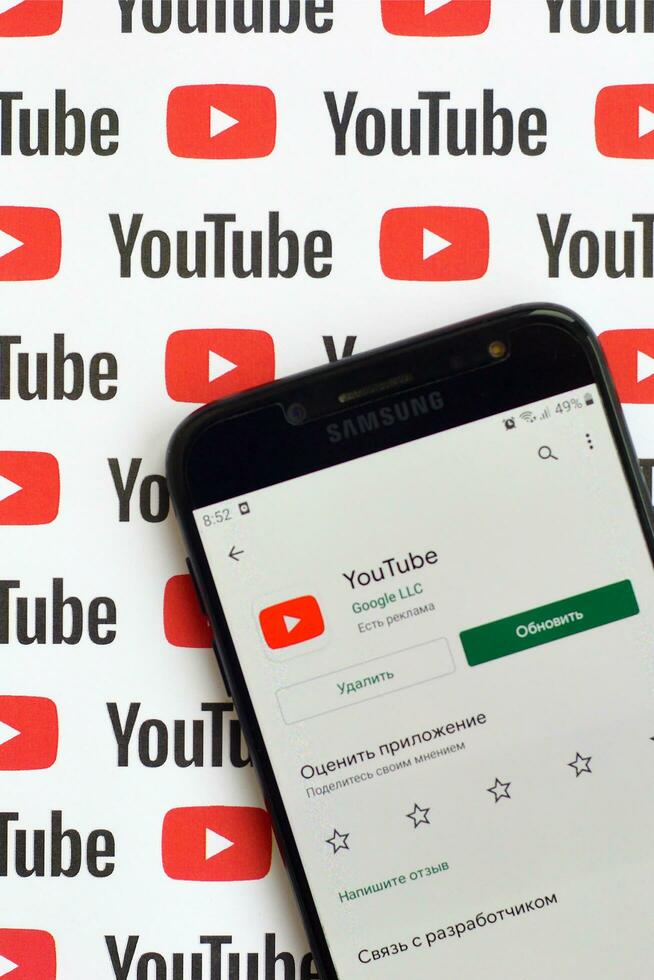 Youtube app on samsung smartphone screen on paper banner with small youtube logos and inscriptions. YouTube is Google subsidiary and American most popular video-sharing platform photo