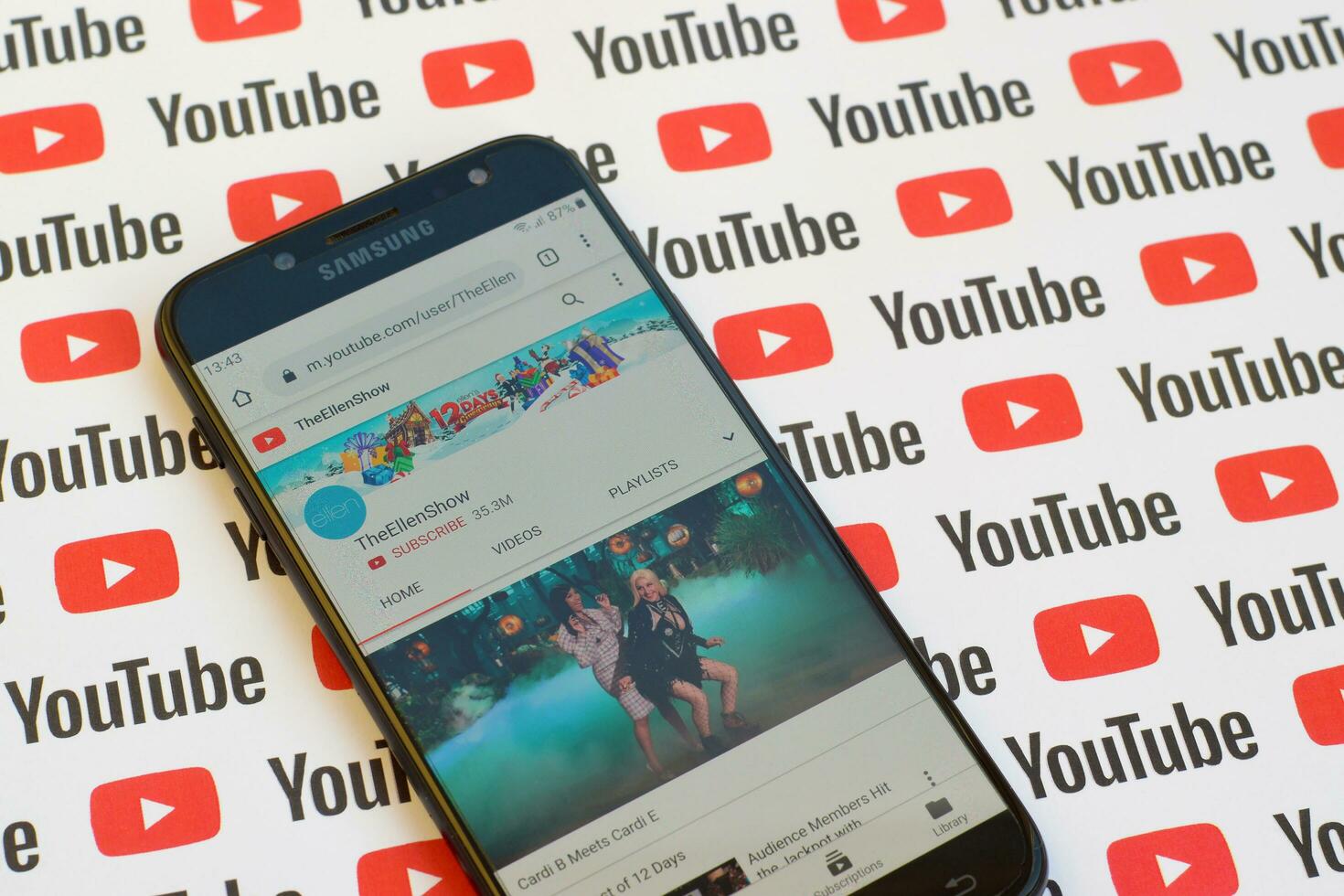 TheEllenShow official youtube channel on smartphone screen on paper youtube background. photo
