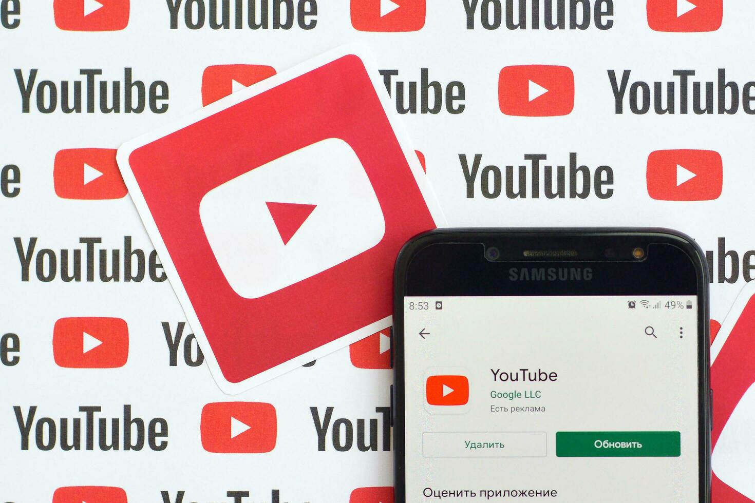 Youtube app on samsung smartphone screen on paper banner with small youtube logos and inscriptions. YouTube is Google subsidiary and American most popular video-sharing platform photo