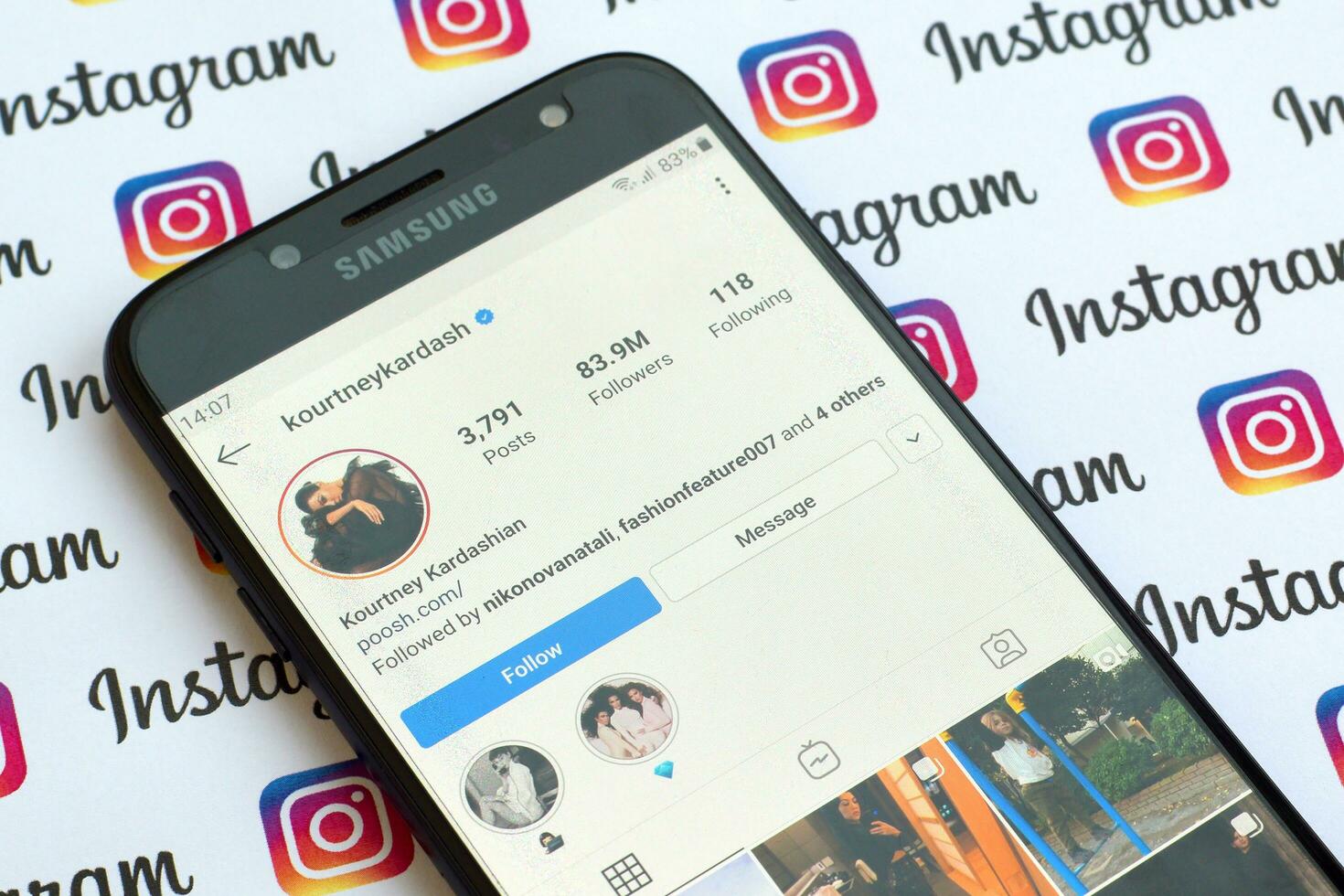 Kourtney Kardashian official instagram account on smartphone screen on paper instagram banner. photo