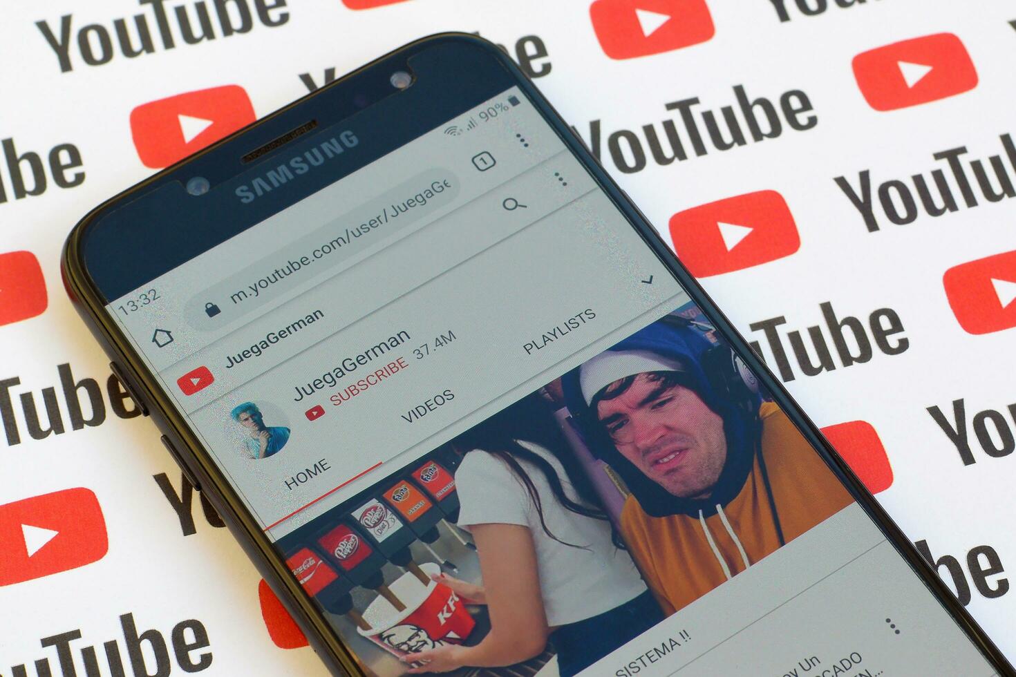 JuegaGerman official youtube channel on smartphone screen on paper youtube background. photo