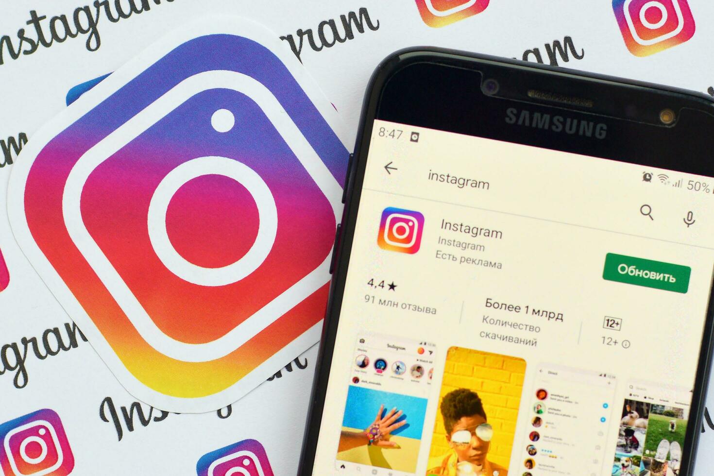 Instagram app on samsung smartphone screen on banner with small instagram logos. Instagram is American photo and video-sharing social networking service by Facebook inc