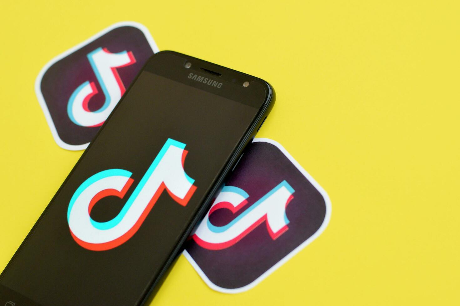 Tiktok logo on samsung smartphone screen on yellow background. TikTok is a popular video-sharing social networking service owned by ByteDance photo