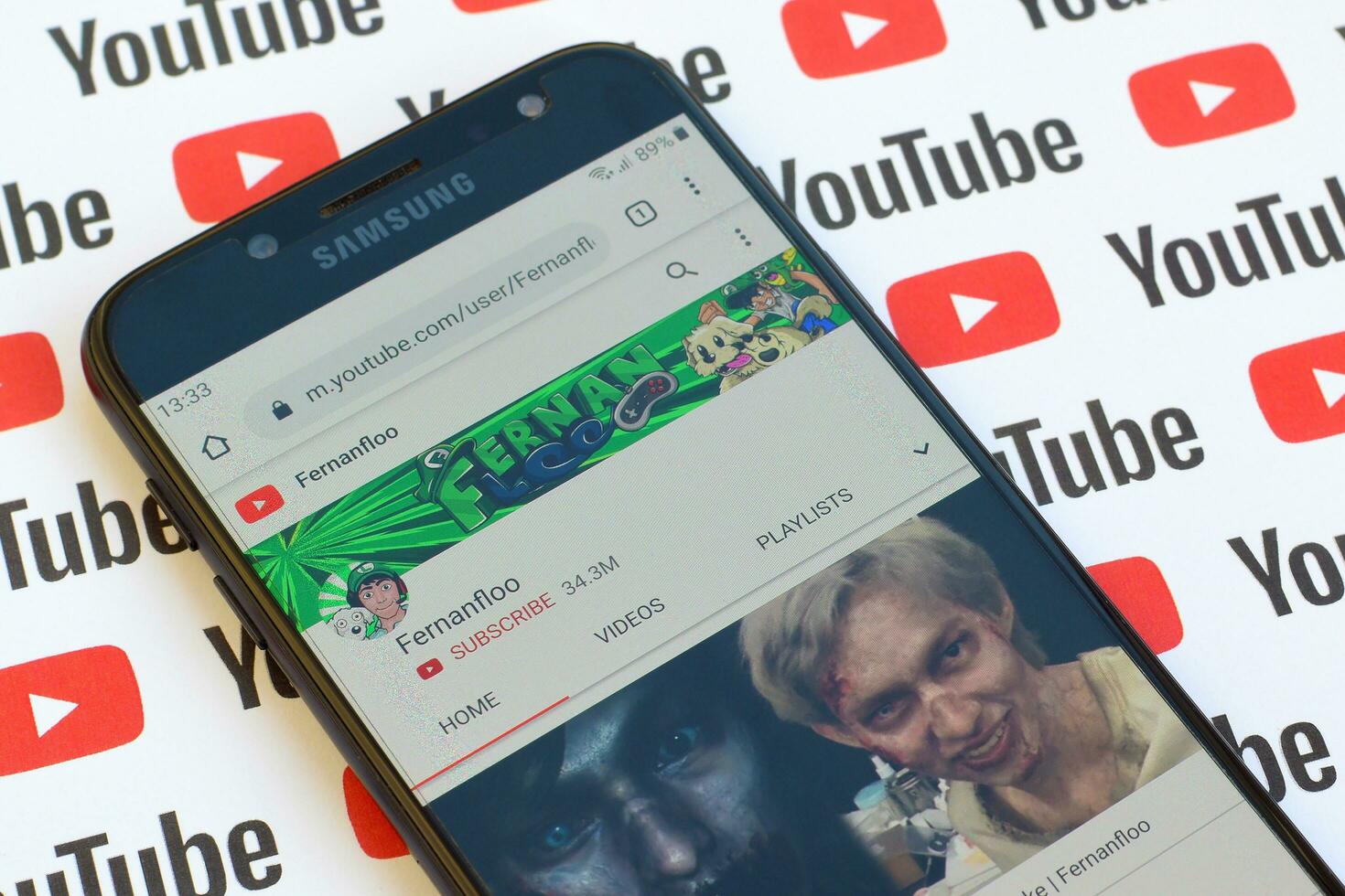 Fernanfloo official youtube channel on smartphone screen on paper youtube background. photo