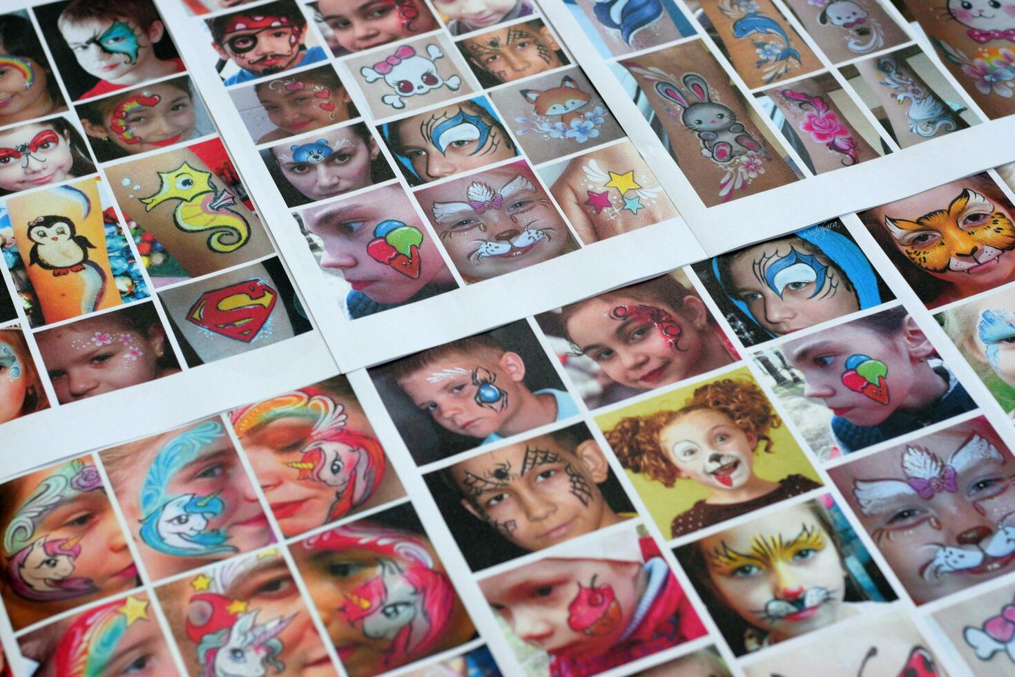 Many catalog pages with printed kids portraits with colorful face painting photo