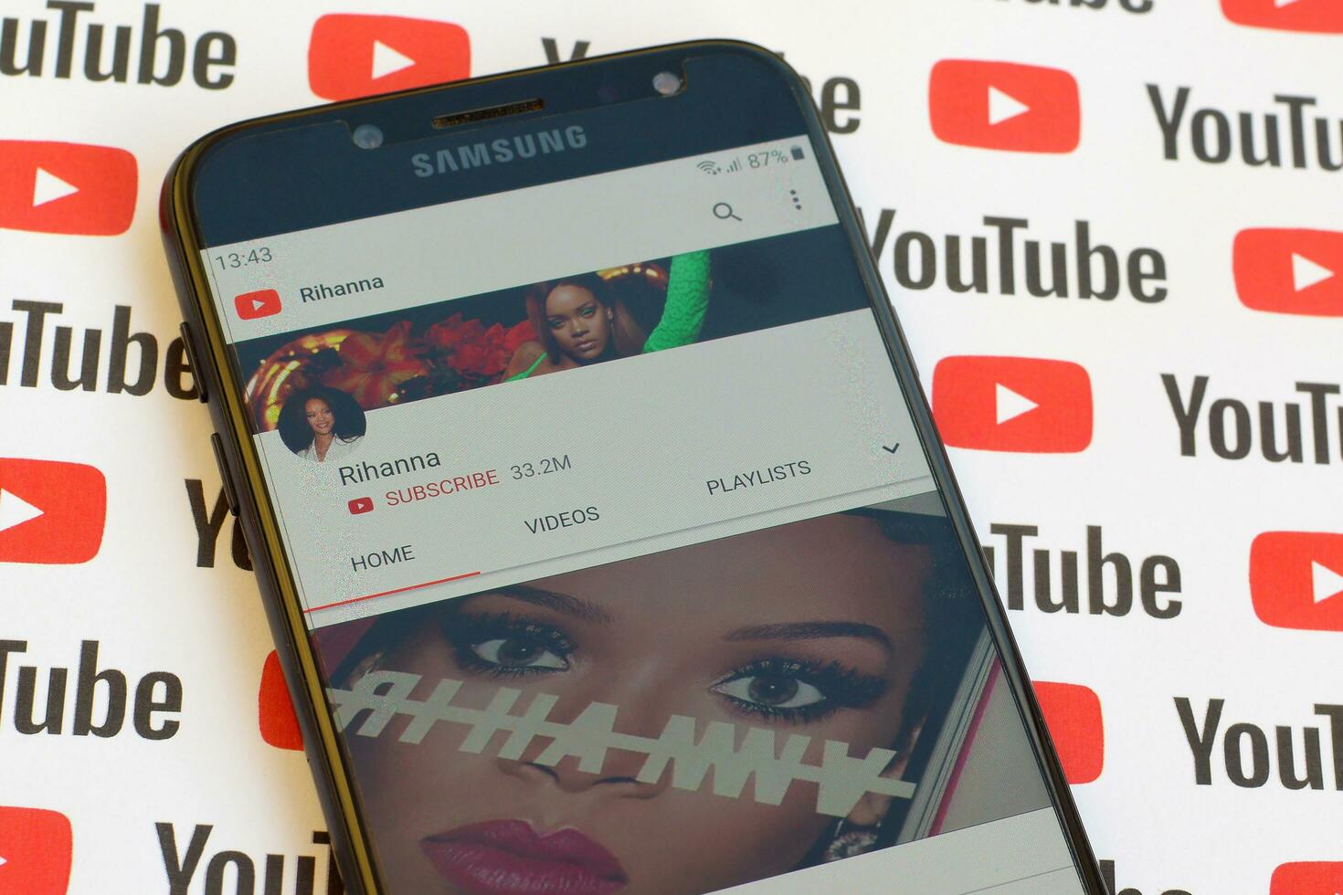 Rihanna official youtube channel on smartphone screen on paper youtube background. photo