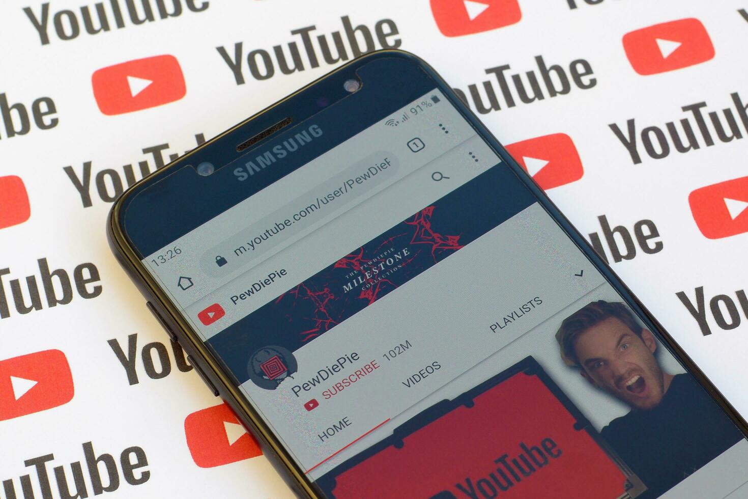 Pewdiepie official youtube channel on smartphone screen on paper youtube background. photo