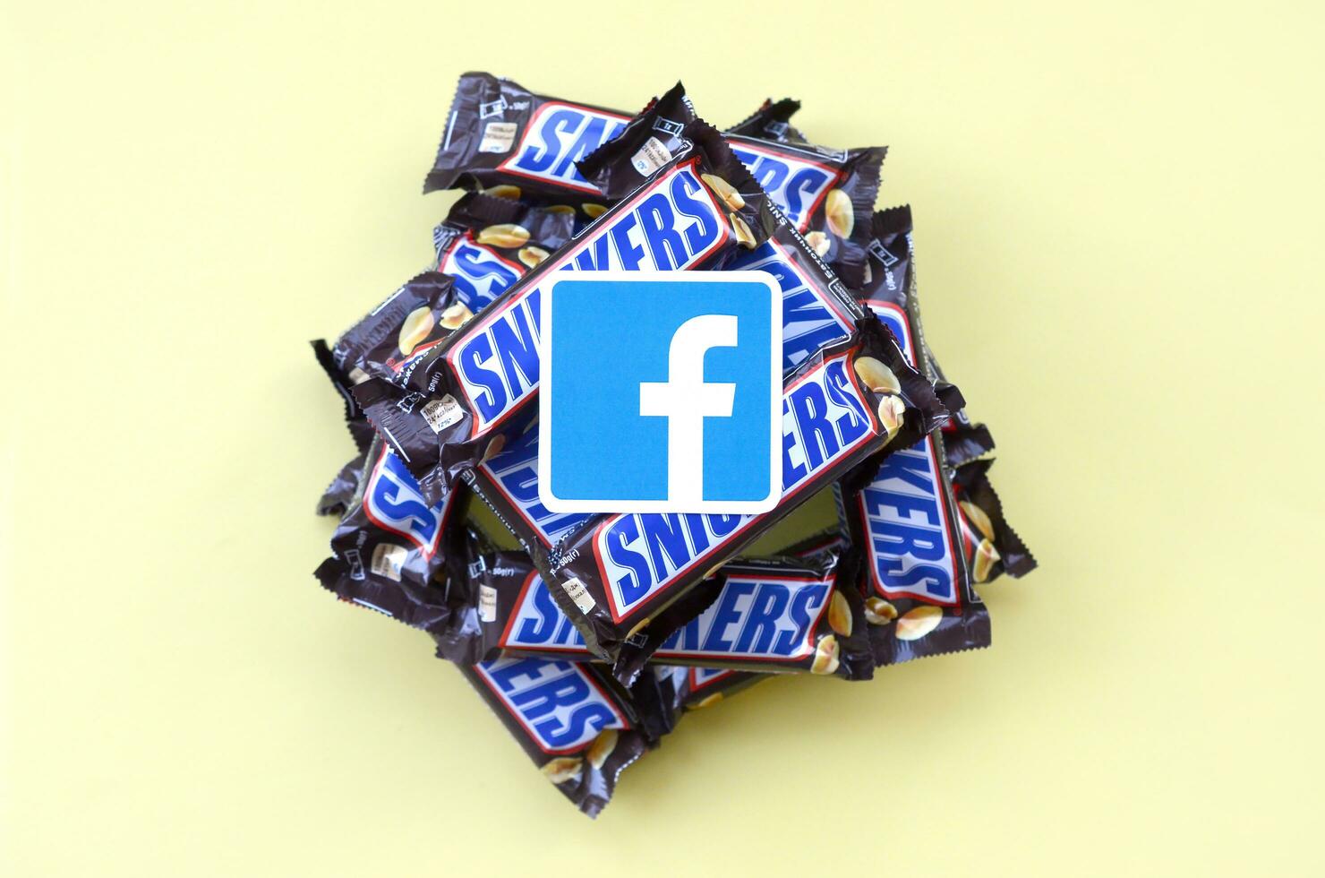 Facebook paper logo on many Snickers chocolate covered wafer bars in brown wrapping. Advertising chocolate product in Facebook social network and world wide web photo