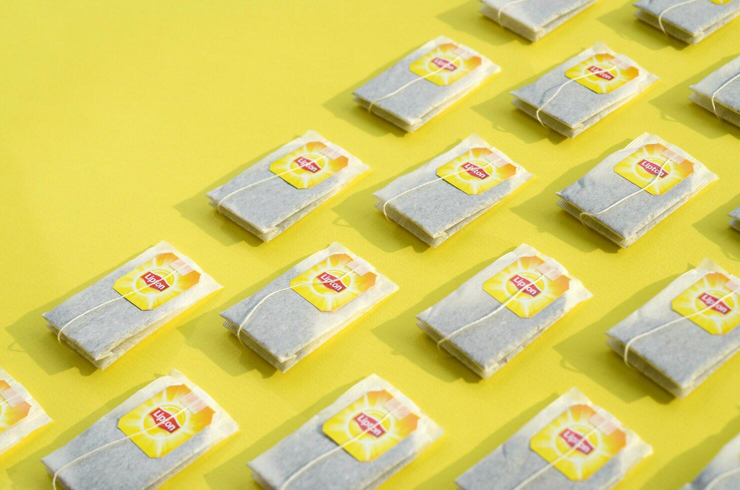 Flat lay of Lipton Yellow Label black tea bags on pastel yellow surface. Lipton is a world famous brand of tea photo