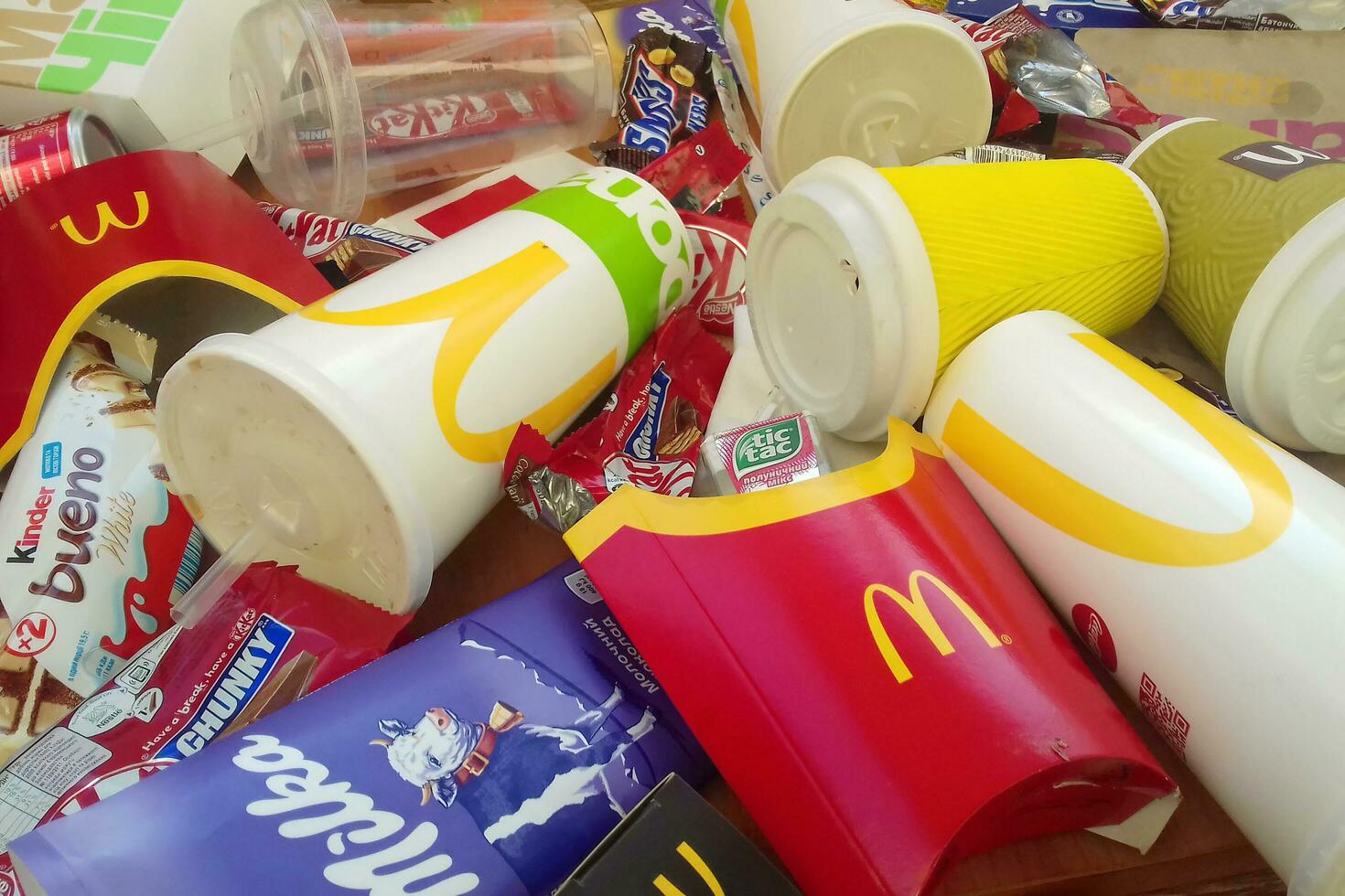 Many used food wrappings and drink cans by random food manufacturing famous brands. Recycled trash of treats and soda drinks photo