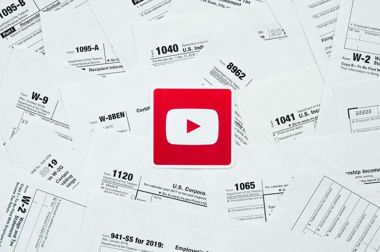 Printed Youtube logo on many tax form blanks lies on table close up. Help with tax problems using internet and information from social networks photo