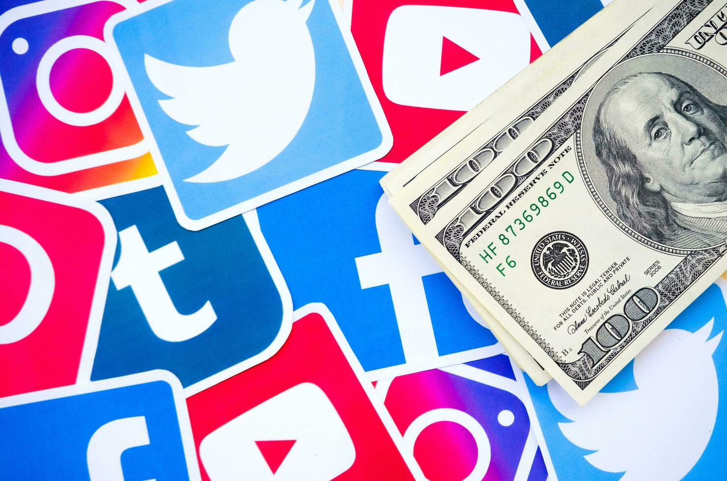 Many hundred dollars bills with printed logo of social networks. Facebook Instagram Youtube Tumblr Twitter Pinterest. Work using internet websites or apps photo