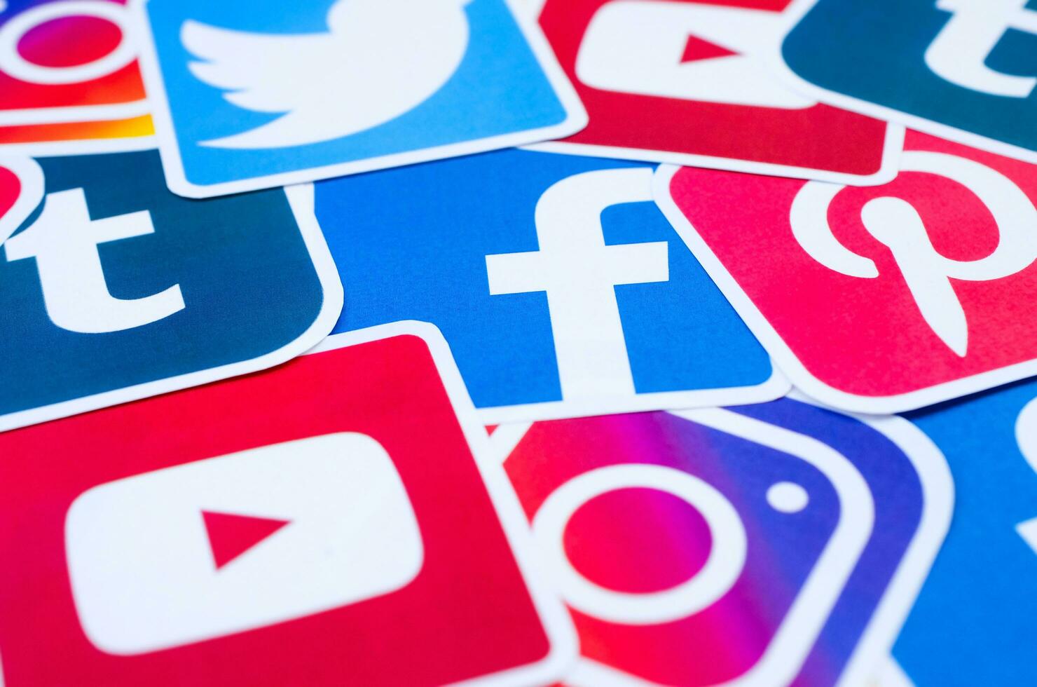 Many social network printed icons lies in pile. Facebook Instagram Pinterest Twitter Youtube Tumblr. Abstract internet background photo