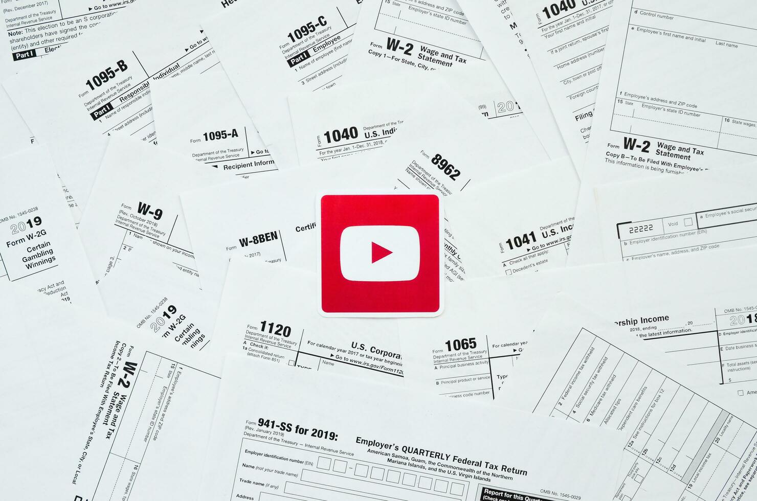 Printed Youtube logo on many tax form blanks lies on table close up. Help with tax problems using internet and information from social networks photo