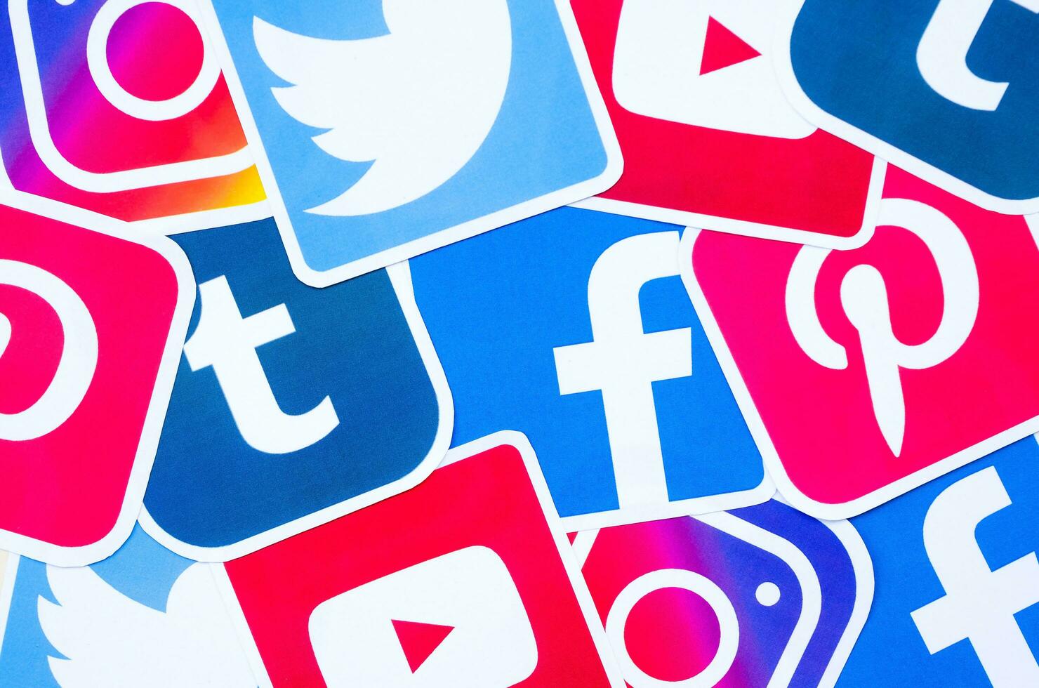 Many social network printed icons lies in pile. Facebook Instagram Pinterest Twitter Youtube Tumblr. Abstract internet background photo