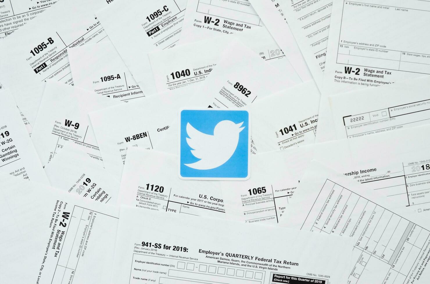 Printed Twitter logo on many tax form blanks lies on table close up. Help with tax problems using internet and information from social networks photo