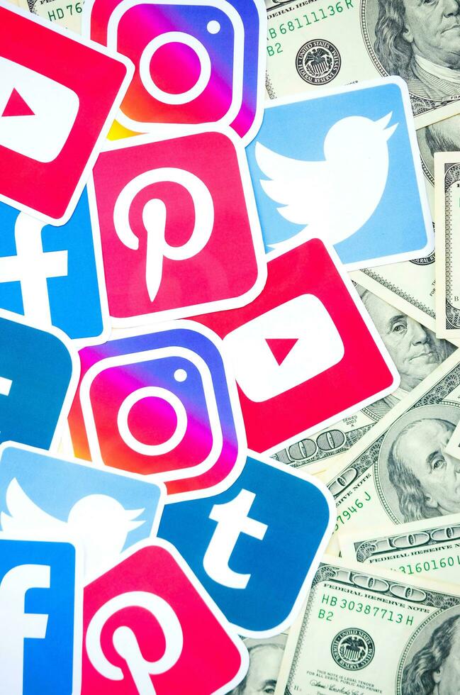 Many hundred dollars bills with printed logo of social networks. Facebook Instagram Youtube Tumblr Twitter Pinterest. Work using internet websites or apps photo
