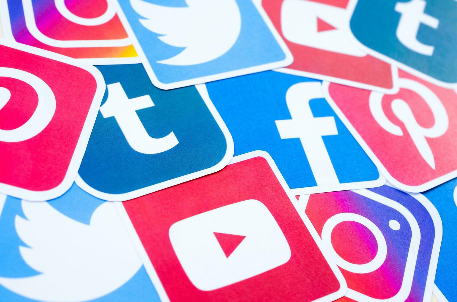 Many social network printed icons lies in pile. Facebook Instagram Pinterest Twitter Youtube Tumblr. Abstract internet background photo