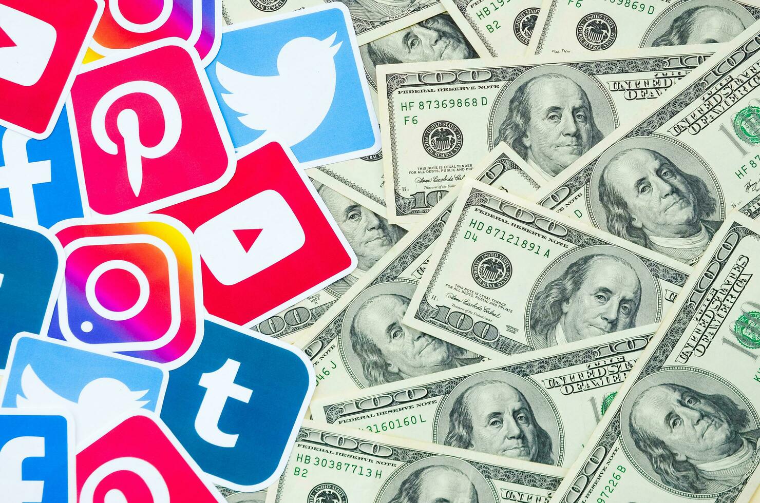 Many hundred dollars bills with printed logo of social networks. Facebook Instagram Youtube Tumblr Twitter Pinterest. Work using internet websites or apps photo