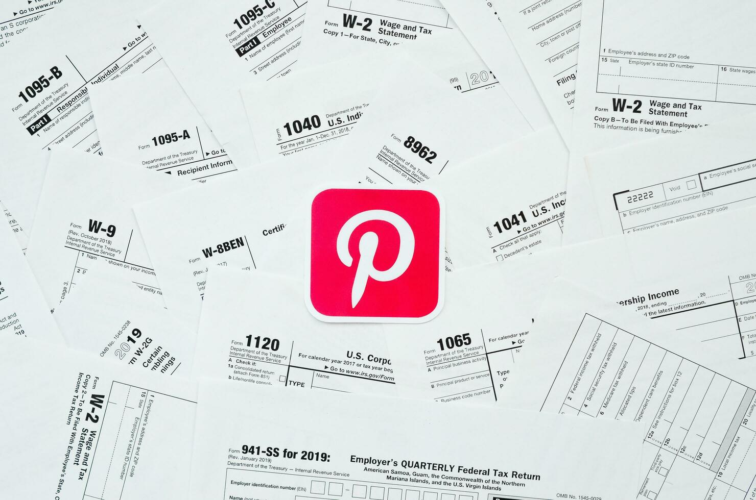 Printed Pinterest logo on many tax form blanks lies on table close up. Help with tax problems using internet and information from social networks photo